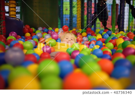 little boy having fun in ball pit with balls little boy having fun in ball pit with balls 48736340