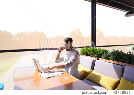 Prosperous sales manager reading documents, using laptop at tabl Prosperous sales manager reading documents, using laptop at tabl 48738981