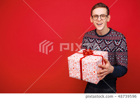 Happy guy in glasses with a gift box in hands Happy guy in glasses with a gift box in hands 48739596