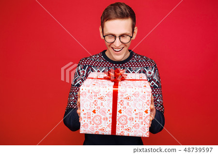 A man in glasses with a gift box in his hands A man in glasses with a gift box in his hands 48739597