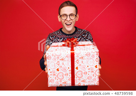 Happy guy in glasses with a gift box in hands Happy guy in glasses with a gift box in hands 48739598
