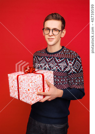 Happy guy in glasses with a gift box in hands Happy guy in glasses with a gift box in hands 48739599