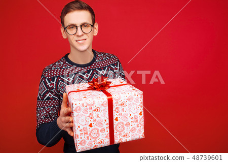 Happy guy in glasses with a gift box in hands Happy guy in glasses with a gift box in hands 48739601