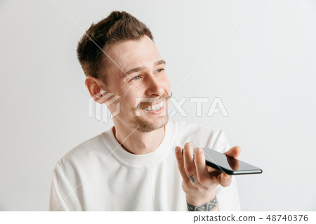 Indoor portrait of attractive young man holding smartphone 48740376