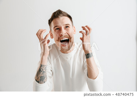 The young emotional angry man screaming on garay studio background The young emotional angry man screaming on garay studio background 48740475