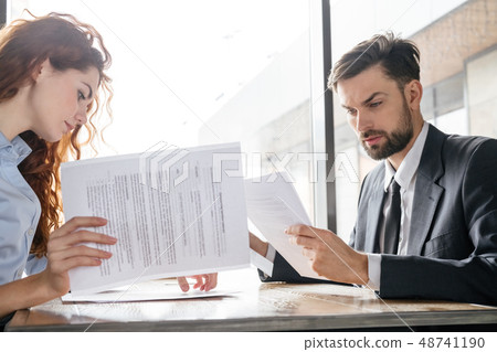 Businesspeople having business lunch at restaurant sitting looking at documents concentrated 48741190