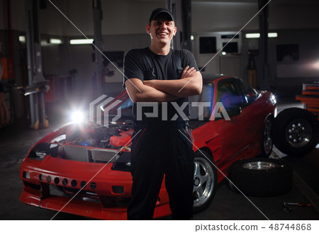 Mecanic in front of the red car. 48744868