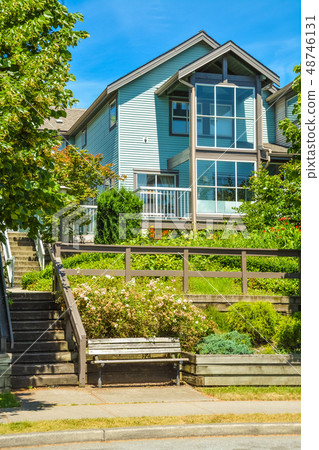 Facade of residential house built on land terrace with wooden bench in front. Facade of residential house built on land terrace with wooden bench in front. 48746131