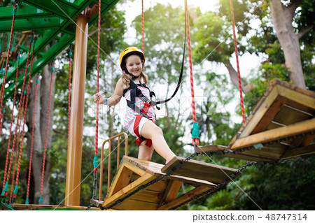 Child in adventure park. Kids climbing rope trail. 48747314