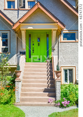 Green entrance door of family house under the porch with the doorsteps in front 48747372