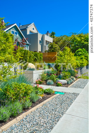 Delicatedly landscaped front yards of residential houses on a street. Delicatedly landscaped front yards of residential houses on a street. 48747374