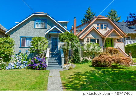 Residential houses with the pathway over front yard lawn on blue sky background 48747403