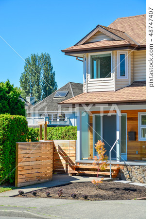Residential house with porch and concrete pathway over the front yard. Residential house with porch and concrete pathway over the front yard. 48747407