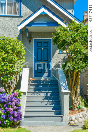 Blue entrance door of family house under the porch with the doorsteps in front Blue entrance door of family house under the porch with the doorsteps in front 48747411