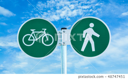 Bicycle and pedestrian shared route sign on cloudy sky background. Bicycle and pedestrian shared route sign on cloudy sky background. 48747451