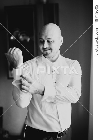 Grooms morning preparation. Handsome man getting dressed and preparing for the wedding Grooms morning preparation. Handsome man getting dressed and preparing for the wedding 48748005