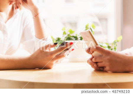 Female hands with smartphones close-up in cafe. Female hands with smartphones close-up in cafe. 48749210
