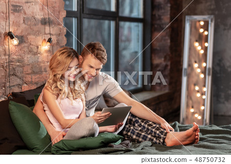 Beaming couple spending happy cozy time together in the bedroom Beaming couple spending happy cozy time together in the bedroom 48750732