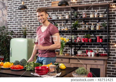 Man with muscles standing in the kitchen and drinking wine Man with muscles standing in the kitchen and drinking wine 48751425