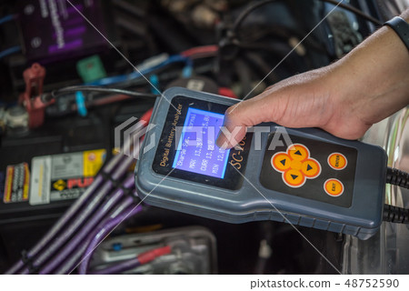 Checking a car battery for repair at car garage 48752590