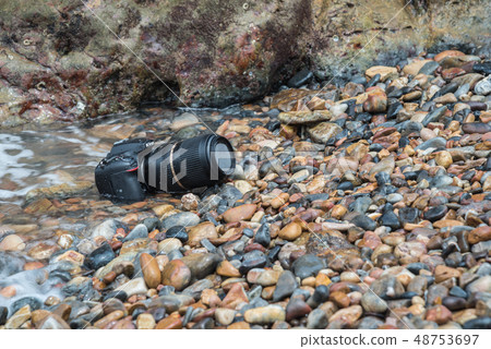 DSLR camera on stone beach wet from water sea wave 48753697