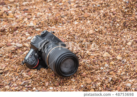 DSLR camera on stone beach wet from water sea wave DSLR camera on stone beach wet from water sea wave 48753698