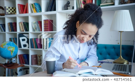 Beautiful african american female student making a marks in the textbooks on preparing for exam at 48754561