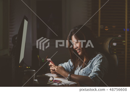 Portrait of Asian Businesswoman sitting and working hard with happiness action on the table with front of computer desktop in workplace at late time, Work hard and too late concept 48756608