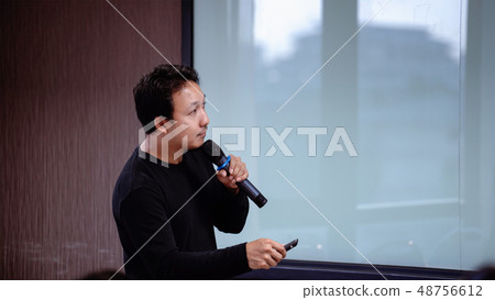 Closeup Asian Speaker or lecture with casual suit on the stage in front of the room presenting with the screen in the conference hall or seminar meeting room, business and education concept 48756612