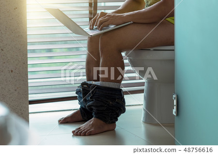 Man using the technology laptop for working when sitting on toilet bowl, hard working concept Man using the technology laptop for working when sitting on toilet bowl, hard working concept 48756616