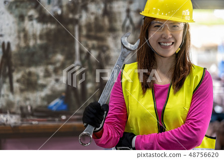 Portrait of Asian machinist in safety suit holding the wrench over the stack of wrench in metalworking factory, lathe grinding metalworking industry concept Portrait of Asian machinist in safety suit holding the wrench over the stack of wrench in metalworking factory, lathe grinding metalworking industry concept 48756620