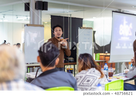 Asian Speaker or lecture with casual suit on the stage in front of the room presenting with the screen in the conference hall or seminar meeting room, business and education concept 48756621