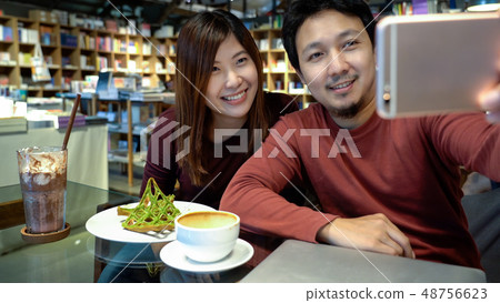 Asian couple taking the selfie with happiness action in modern coffee shop or workplace or co-working space or modern office, lifestyle and leisure concept 48756623