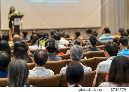 Back side of audience listening the Speaker with podium on the stage in the conference hall, business and education concept Back side of audience listening the Speaker with podium on the stage in the conference hall, business and education concept 48756779