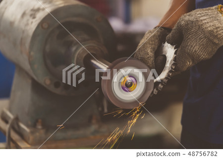 Closeup angle Grinder hand holding and Grinding the spare parts of metal gear in lathe metalworking factory, industry concept 48756782