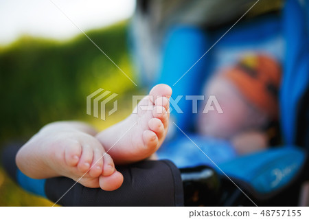 The baby lies in a stroller barefoot. Closeup The baby lies in a stroller barefoot. Closeup 48757155