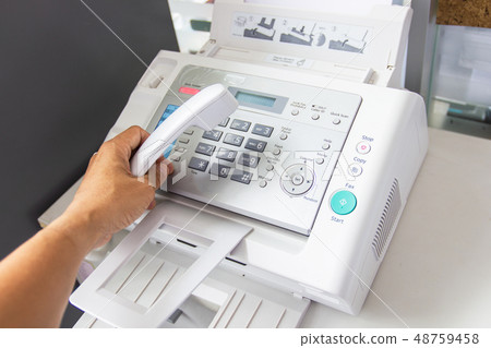hand man are using a fax machine in the office 48759458