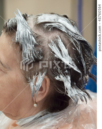 An elderly woman dyes her hair. Close up. 48760564