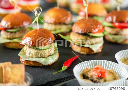 Set of burgers on black board on wooden table 48762998