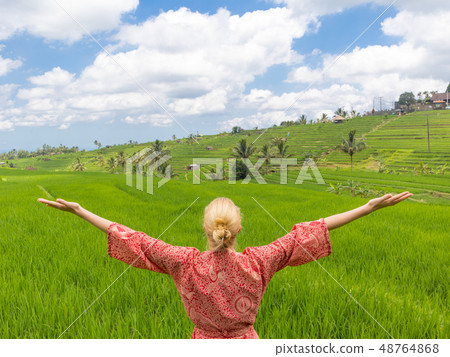 Relaxed fashionable caucasian woman wearing red asian style kimono, arms rised to sky, enjoying pure 48764868