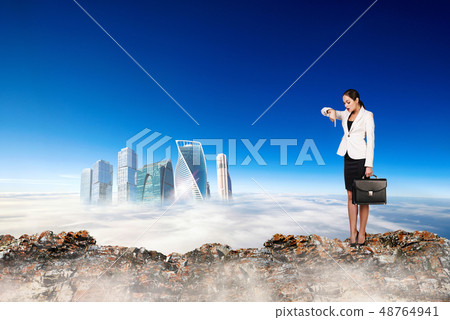 Business woman stands on the edge of mountain and looking on city. Business woman stands on the edge of mountain and looking on city. 48764941