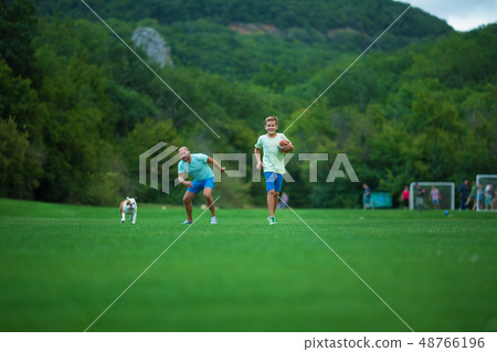 Father and son are running in park with dog 48766196
