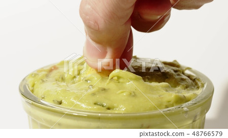 Man dips tortilla chip into guacamole sauce, close-up shot Man dips tortilla chip into guacamole sauce, close-up shot 48766579