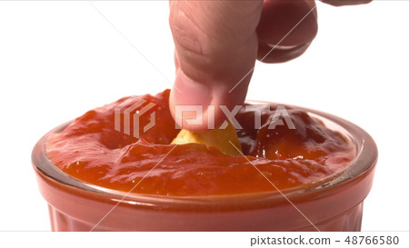 Man dips tortilla chip into red hot salsa sauce, close-up shot Man dips tortilla chip into red hot salsa sauce, close-up shot 48766580