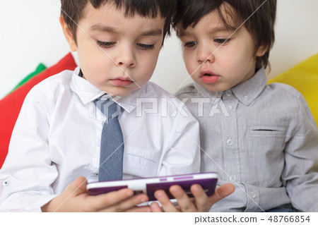 Two boys carefully watching video on smartphone. Learn modern techniques in childhood. Two boys carefully watching video on smartphone. Learn modern techniques in childhood. 48766854