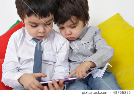 Two boys carefully watching video on smartphone. Learn modern techniques in childhood. Two boys carefully watching video on smartphone. Learn modern techniques in childhood. 48766855