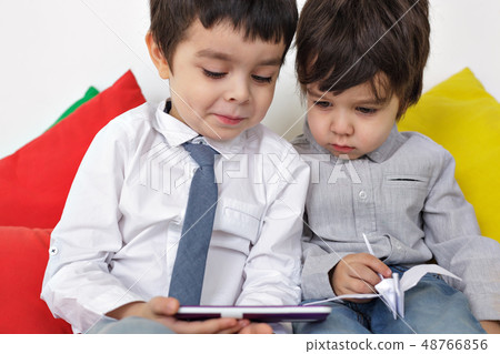Two boys carefully watching video on smartphone. Learn modern techniques in childhood. Two boys carefully watching video on smartphone. Learn modern techniques in childhood. 48766856