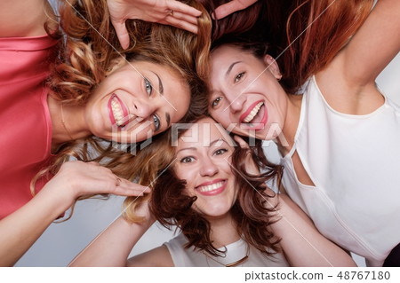 Three happy woman friends looking down Three happy woman friends looking down 48767180