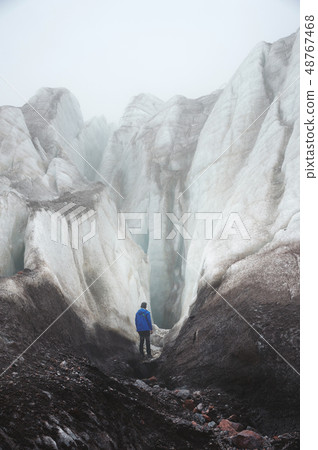 A free climber with an ice ax stands at the foot of the Great Glacier next to an epic crack in the 48767468