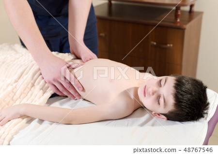 A little boy at the reception at a professional masseuse. Male manual worker gives massage to the 48767546